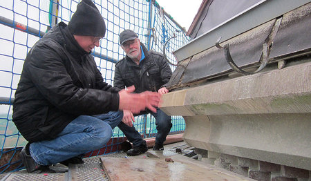 Werner Grage (li.) und Horst Diestel an der Traufe des Turmes (Übergang von Turmstumpf zum Turmhelm). Hier ist das bereits durch den Steinmetz reparierte Sandsteintraufgesims zu sehen und die lose Kupferblecheindeckung. Der untere Teil der Kupferblecheindeckung ist entfernt worden.