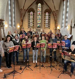 Ein großer Posaunenchor steht in einer Kirche. 